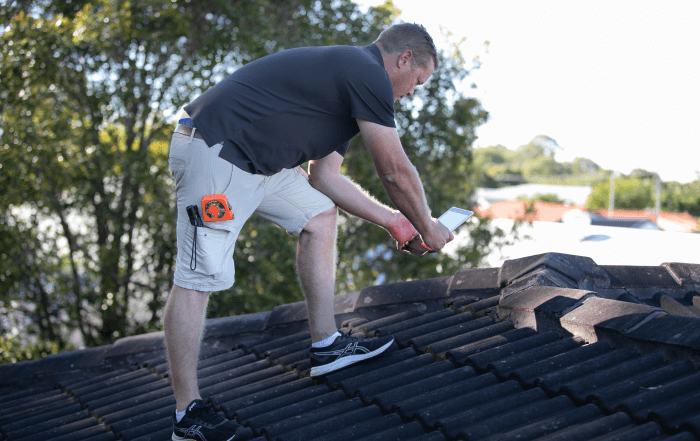 Building inspector checks roof for damage during summer storms
