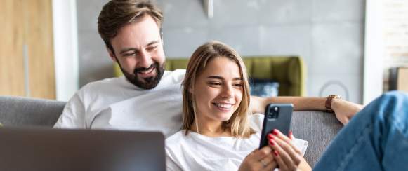 Man and woman on couch managing real estate on a mobile phone